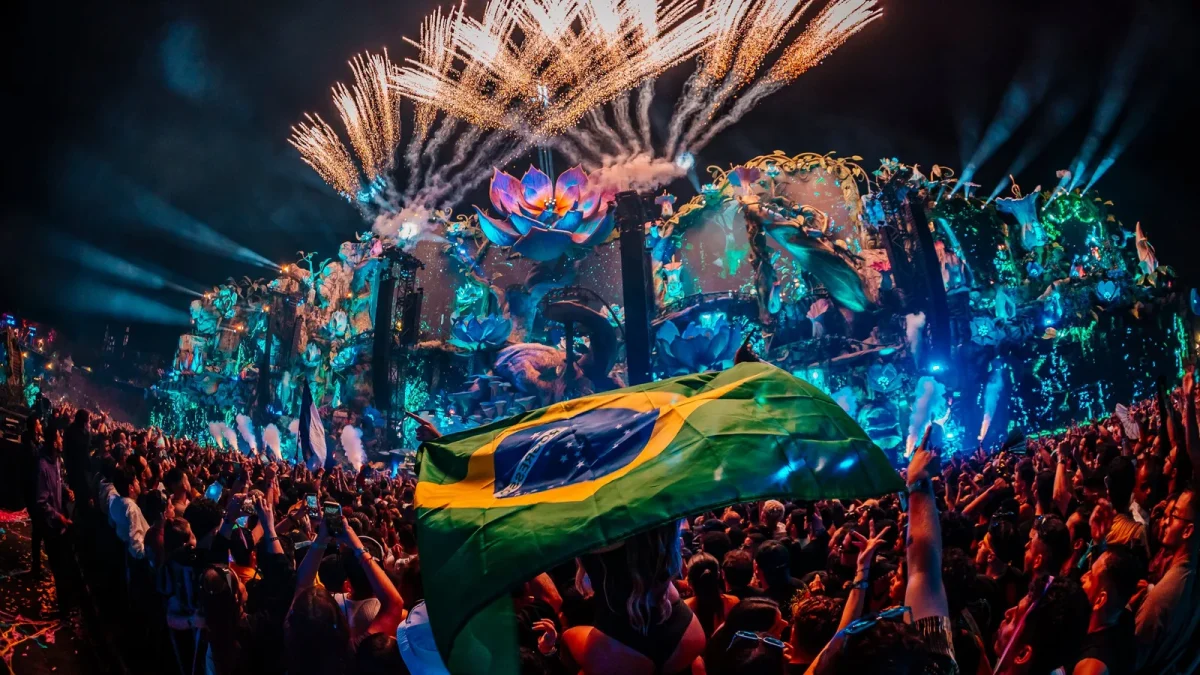 Bandeira do Brasil erguida no meio do público, diante do Mainstage iluminado
