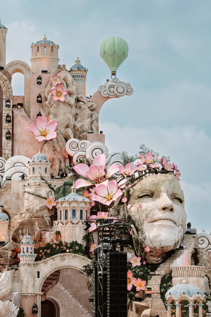 Detalhe do mainstage: um rosto de pedra coroado de flores cor de rosa, com um balão ao fundo