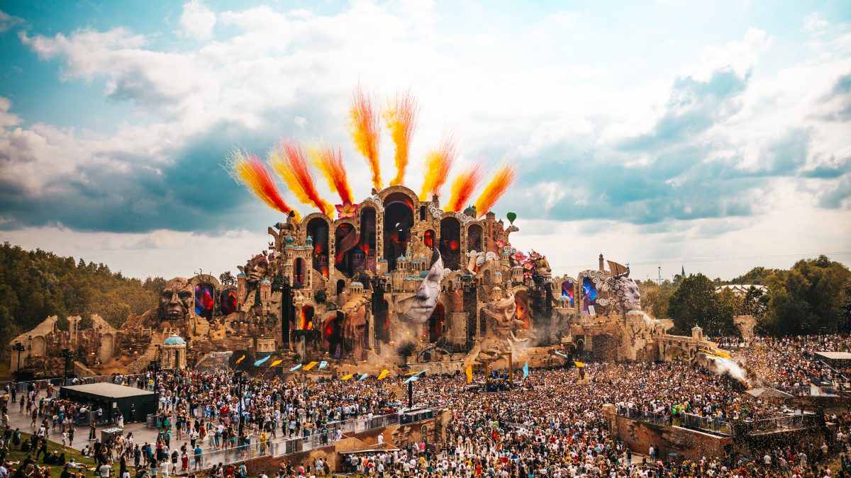 Vista do Mainstage do Tomorrowland na Bélgica durante o dia, com o público e efeitos coloridos no céu.